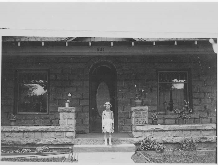 Image of a girl standing on the steps of a home with a sign for the Morning Star Mine
